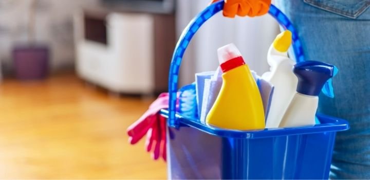 Woman in rubber gloves with bucket of cleaning supplies ready to clean up